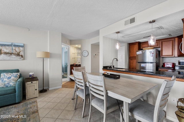 2000 New River Inlet Rd Unit 3513, North Topsail Beach, NC 28460 - kitchen featuring freestanding refrigerator, a textured ceiling, dark countertops, light tile patterned floors, and pendant lighting