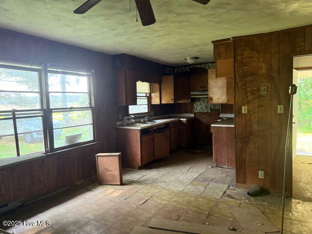120 Bazemore Ln, Sunbury, NC 27979 - kitchen with ceiling fan, under cabinet range hood, wood walls, light countertops, and a textured ceiling