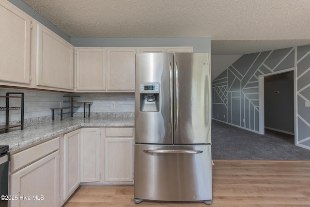 6723 Newbury Way, Wilmington, NC 28411 - kitchen with stainless steel fridge, light wood-style flooring, a textured ceiling, decorative backsplash, and light stone counters
