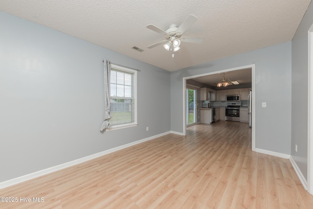6723 Newbury Way, Wilmington, NC 28411 - unfurnished living room with light wood finished floors, a chandelier, ceiling fan, and a textured ceiling