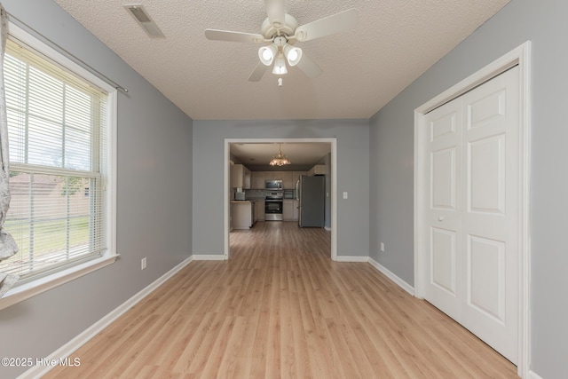 6723 Newbury Way, Wilmington, NC 28411 - unfurnished living room with light wood-style floors, a chandelier, a textured ceiling, and ceiling fan