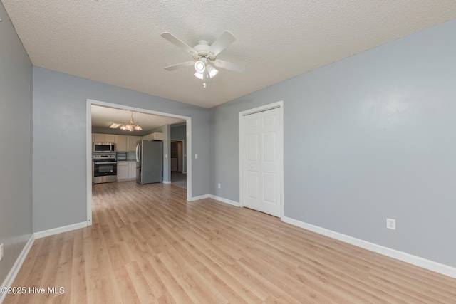 6723 Newbury Way, Wilmington, NC 28411 - unfurnished living room featuring a chandelier, light wood-style flooring, a ceiling fan, and a textured ceiling