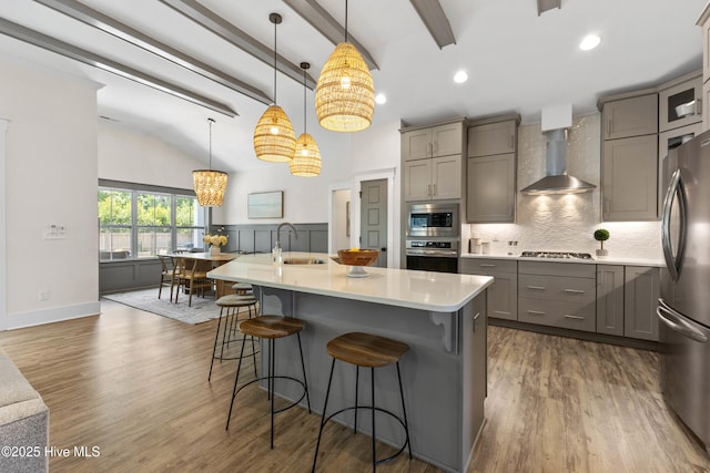 1112 Winged Seed Way, Wilmington, NC 28409 - kitchen featuring gray cabinetry, wall chimney range hood, appliances with stainless steel finishes, light countertops, and a kitchen bar