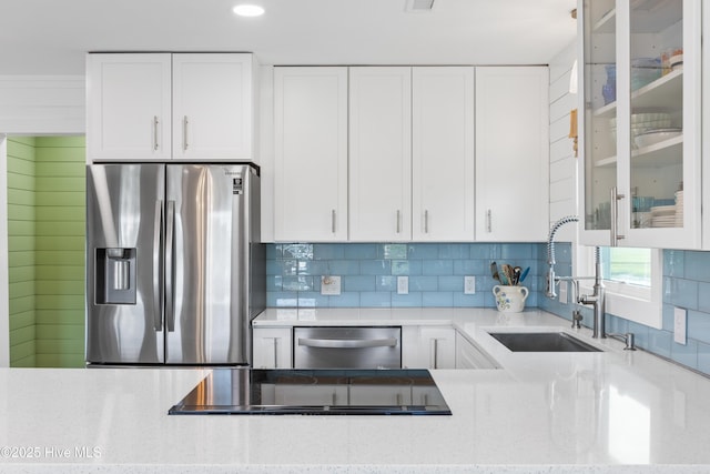 15 Coral Dr, Wrightsville Beach, NC 28480 - kitchen with appliances with stainless steel finishes, tasteful backsplash, glass insert cabinets, light stone countertops, and white cabinetry
