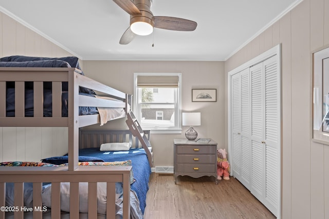 15 Coral Dr, Wrightsville Beach, NC 28480 - bedroom featuring wood finished floors, crown molding, wood walls, a closet, and a ceiling fan