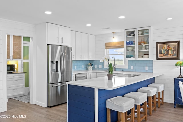 15 Coral Dr, Wrightsville Beach, NC 28480 - kitchen with appliances with stainless steel finishes, light wood finished floors, a kitchen breakfast bar, a peninsula, and white cabinets