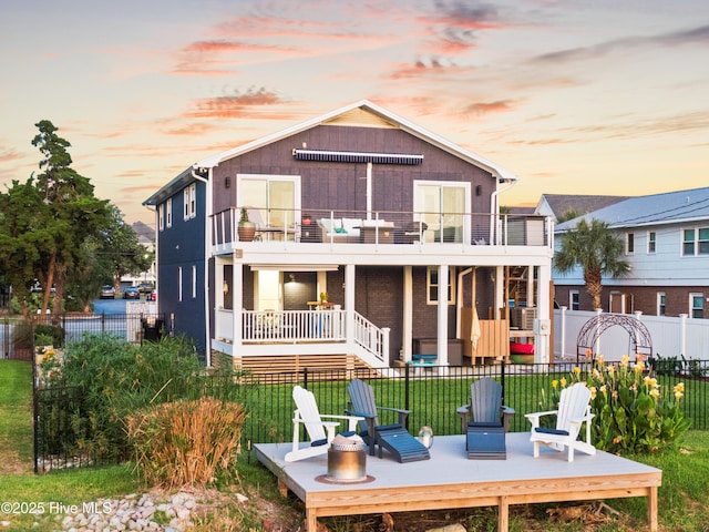 15 Coral Dr, Wrightsville Beach, NC 28480 - back of property at dusk featuring a balcony and a fenced backyard