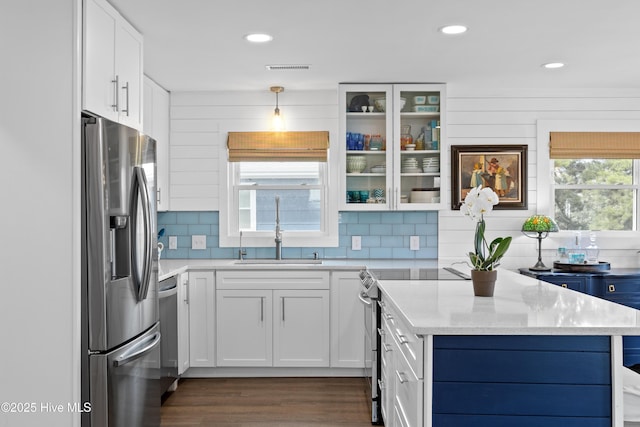 15 Coral Dr, Wrightsville Beach, NC 28480 - kitchen with appliances with stainless steel finishes, white cabinets, tasteful backsplash, dark wood finished floors, and glass insert cabinets