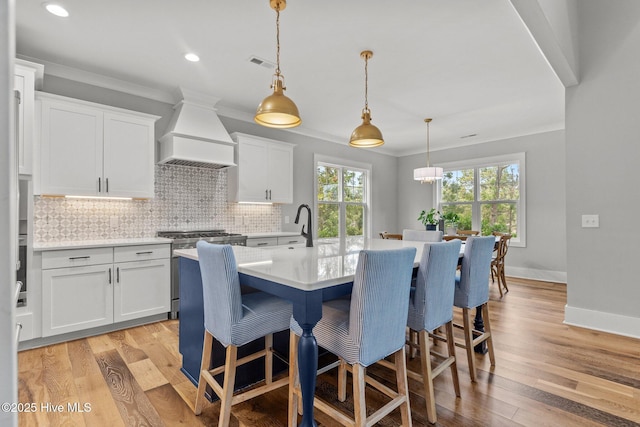 28 Kahkwa Trl, Pinehurst, NC 28374 - kitchen with premium range hood, stainless steel gas range oven, ornamental molding, backsplash, and a breakfast bar area