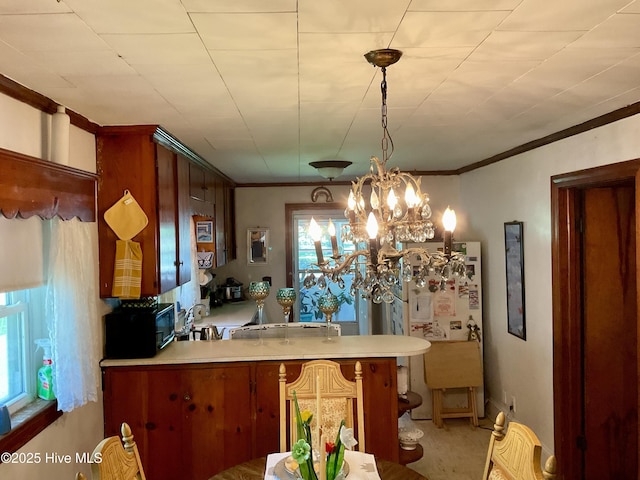309 Battle Dr, Nashville, NC 27856 - kitchen featuring a peninsula, light countertops, black microwave, ornamental molding, and hanging light fixtures