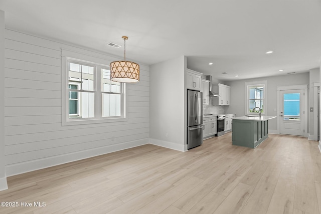 207 Spartanburg Ave Unit 1 & 2, Carolina Beach, NC 28428 - kitchen featuring appliances with stainless steel finishes, wall chimney range hood, light wood-style floors, light countertops, and recessed lighting
