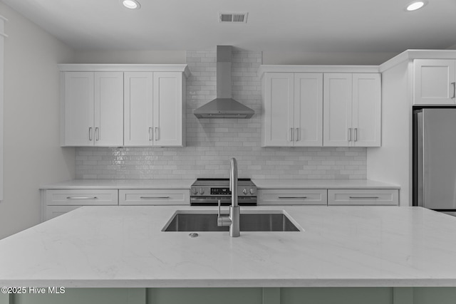207 Spartanburg Ave Unit 1 & 2, Carolina Beach, NC 28428 - kitchen featuring wall chimney exhaust hood, appliances with stainless steel finishes, white cabinets, recessed lighting, and light stone counters