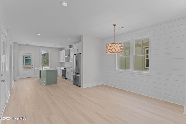 207 Spartanburg Ave Unit 1 & 2, Carolina Beach, NC 28428 - kitchen featuring stainless steel appliances, light countertops, light wood-type flooring, an island with sink, and wall chimney range hood