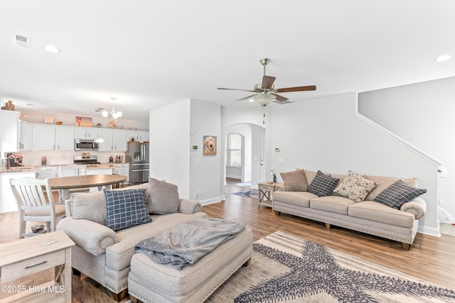 2526 Longleaf Pine Cir, Leland, NC 28451 - living room featuring arched walkways, light wood finished floors, a ceiling fan, recessed lighting, and a chandelier