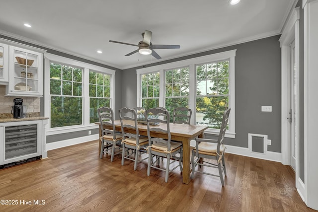 318 Cabbage Inlet Ln, Wilmington, NC 28409 - dining room featuring beverage cooler, ornamental molding, a ceiling fan, wood finished floors, and plenty of natural light