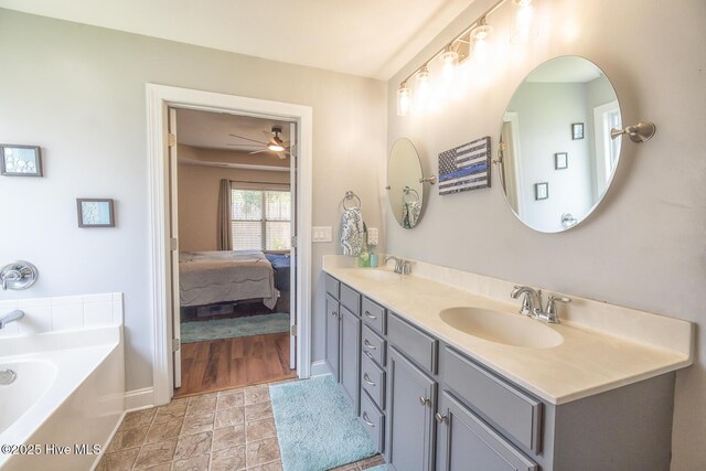 1247 Dunlop Dr NE, Leland, NC 28451 - ensuite bathroom featuring double vanity, a ceiling fan, a garden tub, and stone finish floors