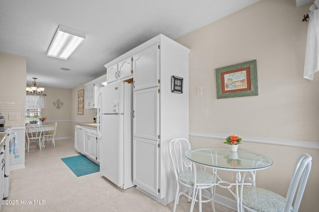 58 Crystal Rd, Southport, NC 28461 - kitchen featuring freestanding refrigerator, white cabinets, a chandelier, light countertops, and backsplash