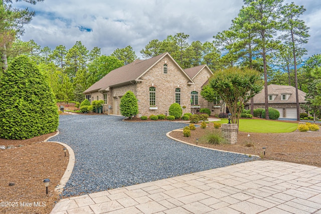 56 Kilbride Dr, Pinehurst, NC 28374 - view of front facade with brick siding, gravel driveway, a shingled roof, and an attached garage
