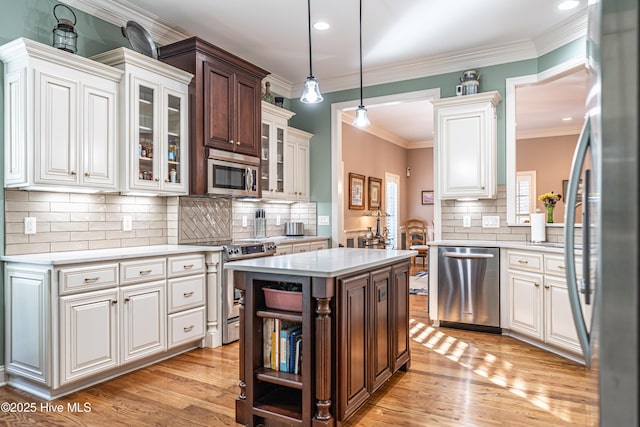 56 Kilbride Dr, Pinehurst, NC 28374 - kitchen featuring stainless steel appliances, light countertops, tasteful backsplash, light wood-type flooring, and crown molding