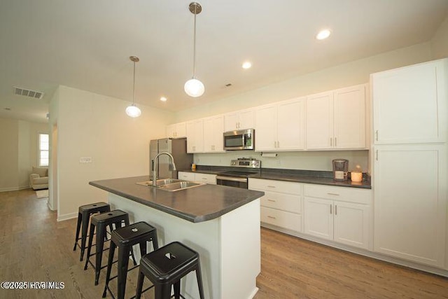 146 Poplar St, Jacksonville, NC 28540 - kitchen featuring stainless steel appliances, dark countertops, an island with sink, wood finished floors, and a breakfast bar