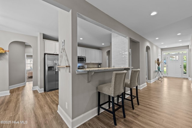 16 Starlit Ln, Pinehurst, NC 28374 - kitchen featuring appliances with stainless steel finishes, arched walkways, a breakfast bar, light wood finished floors, and recessed lighting
