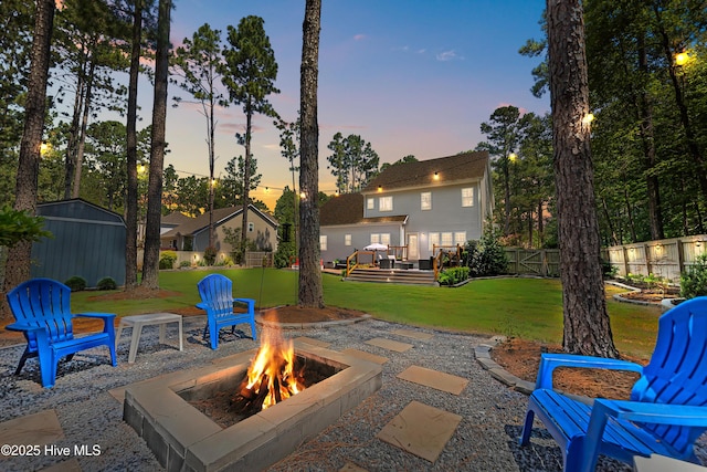 16 Starlit Ln, Pinehurst, NC 28374 - patio terrace at dusk featuring an outdoor fire pit, a deck, and a storage unit