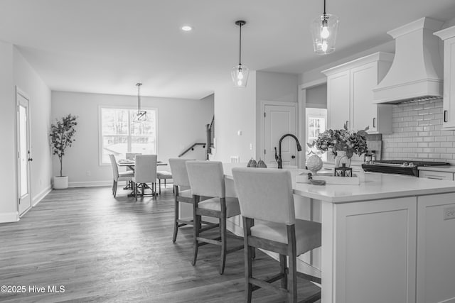 1165 Burning Tree Rd, Pinehurst, NC 28374 - kitchen featuring custom range hood, decorative backsplash, light countertops, light wood-style floors, and white cabinetry
