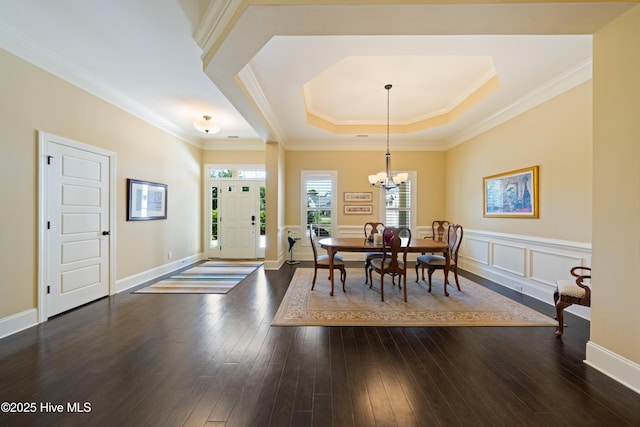 2675 Four Oak Rd, Southport, NC 28461 - dining room featuring a tray ceiling, a chandelier, dark wood-style flooring, crown molding, and wainscoting