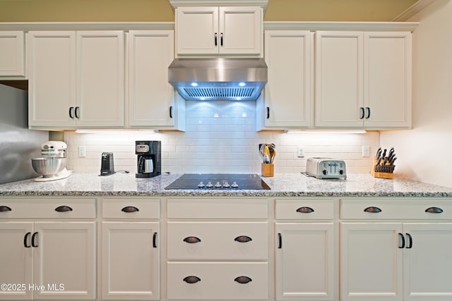 2675 Four Oak Rd, Southport, NC 28461 - kitchen featuring black electric stovetop, wall chimney exhaust hood, white cabinets, decorative backsplash, and light stone counters