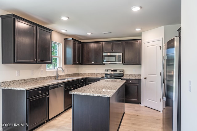 481 Peggy Mill Rd, Hamlet, NC 28345 - kitchen featuring appliances with stainless steel finishes, light wood-style flooring, light stone countertops, a kitchen island, and dark brown cabinetry