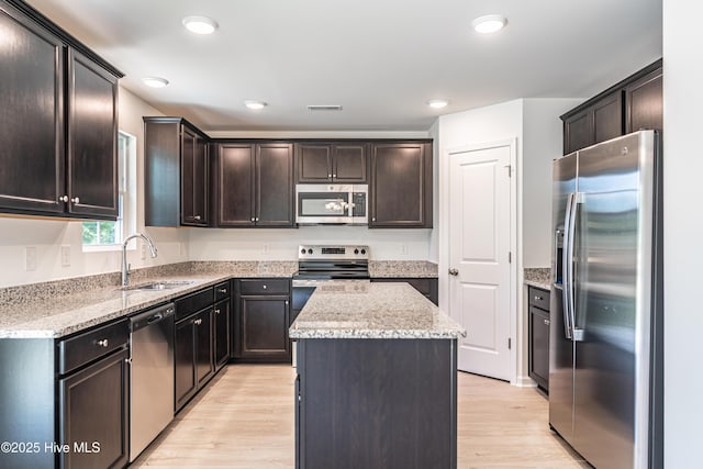 481 Peggy Mill Rd, Hamlet, NC 28345 - kitchen with appliances with stainless steel finishes, a center island, light wood-style floors, light stone countertops, and dark brown cabinets