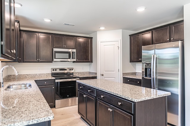 481 Peggy Mill Rd, Hamlet, NC 28345 - kitchen featuring stainless steel appliances, dark brown cabinets, a center island, light stone countertops, and recessed lighting
