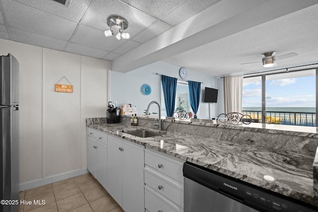 901 Lake Park Blvd S Unit 201, Carolina Beach, NC 28428 - kitchen with stainless steel appliances, light tile patterned flooring, a paneled ceiling, white cabinetry, and light stone countertops