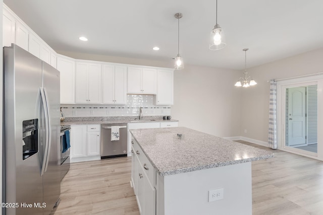 107 Pasture Ln Unit B, Swansboro, NC 28584 - kitchen featuring stainless steel appliances, light wood-style floors, decorative backsplash, a chandelier, and white cabinetry