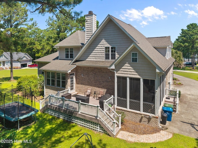 106 Blue Heron Cir, Sneads Ferry, NC 28460 - back of property with a trampoline, a chimney, a sunroom, roof with shingles, and a yard