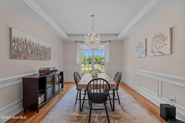 106 Blue Heron Cir, Sneads Ferry, NC 28460 - dining area featuring a chandelier, a raised ceiling, wood finished floors, a wainscoted wall, and crown molding
