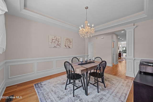 106 Blue Heron Cir, Sneads Ferry, NC 28460 - dining area with a chandelier, a raised ceiling, light wood-type flooring, crown molding, and wainscoting