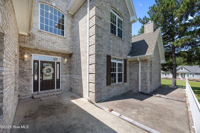 106 Blue Heron Cir, Sneads Ferry, NC 28460 - doorway to property with a chimney, a shingled roof, brick siding, and a patio