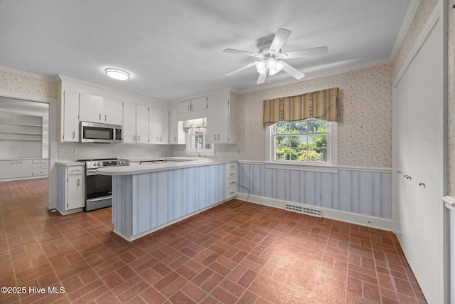 1902 York St, Kinston, NC 28504 - kitchen featuring appliances with stainless steel finishes, wallpapered walls, ornamental molding, brick patterned flooring, and light countertops