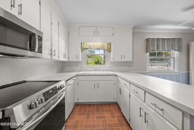 1902 York St, Kinston, NC 28504 - kitchen featuring appliances with stainless steel finishes, wallpapered walls, brick patterned flooring, light countertops, and a wainscoted wall