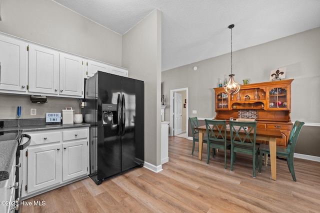 2824 Preston Ln, Grimesland, NC 27837 - kitchen featuring black fridge with ice dispenser, light wood-style flooring, white cabinetry, dark countertops, and pendant lighting