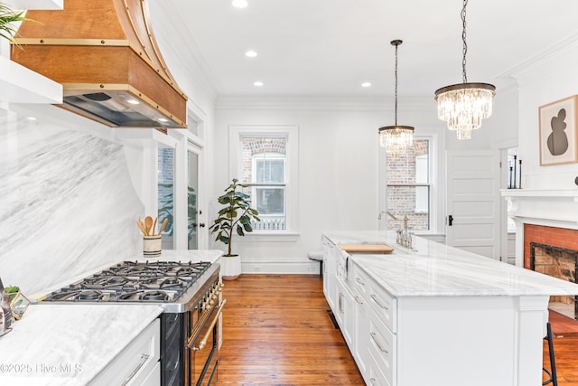 503 S 3rd St, Wilmington, NC 28401 - kitchen with stainless steel range with gas cooktop, ornamental molding, custom exhaust hood, a kitchen bar, and hardwood / wood-style flooring