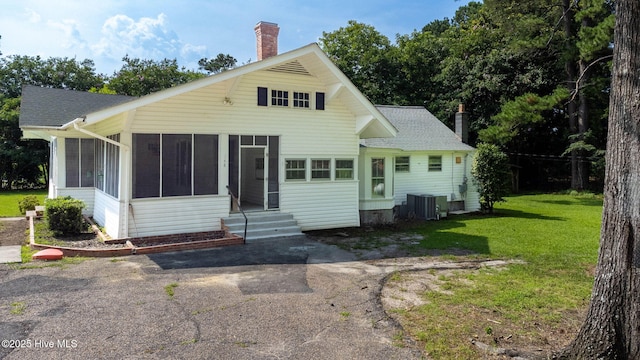 148 N Mitchell Ford Rd, Clarkton, NC 28433 - back of house with a chimney, a sunroom, a shingled roof, and a lawn