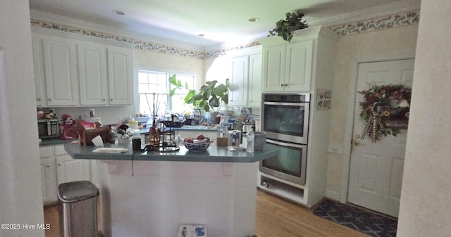 3129 Lake Pointe Trl, Rocky Mount, NC 27804 - kitchen with appliances with stainless steel finishes, dark countertops, white cabinets, wood finished floors, and crown molding
