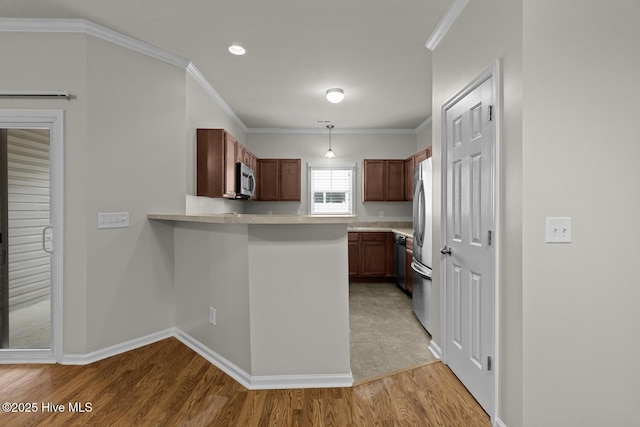 231 Glenhaven Ln, Jacksonville, NC 28546 - kitchen with light countertops, a peninsula, stainless steel appliances, pendant lighting, and light wood-style floors