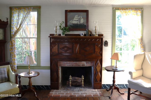 212 Carteret St, Bath, NC 27808 - sitting room featuring wood walls, healthy amount of natural light, wood finished floors, and a brick fireplace