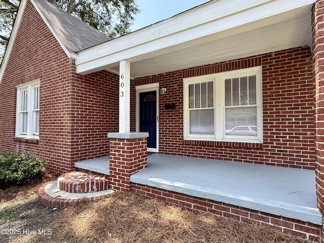 603 E 8th St, Washington, NC 27889 - view of exterior entry with brick siding, a porch, and roof with shingles
