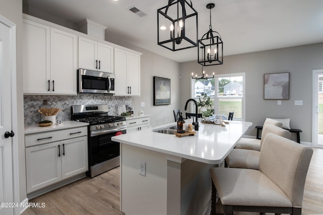 301 Glassmine Trl Unit 48, Aberdeen, NC 28315 - kitchen with appliances with stainless steel finishes, a chandelier, light wood-style floors, decorative backsplash, and a center island with sink