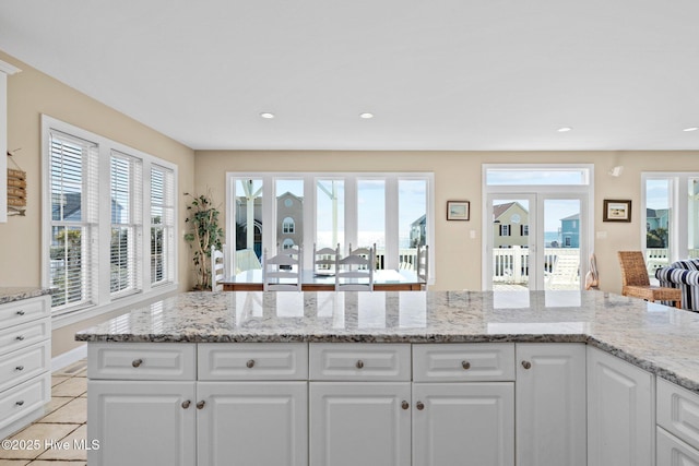 9711 Dolphin Ridge Rd, Emerald Isle, NC 28594 - kitchen featuring healthy amount of natural light, white cabinets, light tile patterned floors, light stone counters, and recessed lighting