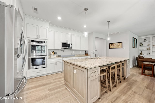 145 Beechnut Ave, South Mills, NC 27976 - kitchen featuring appliances with stainless steel finishes, light wood-type flooring, a kitchen island with sink, white cabinets, and a breakfast bar area